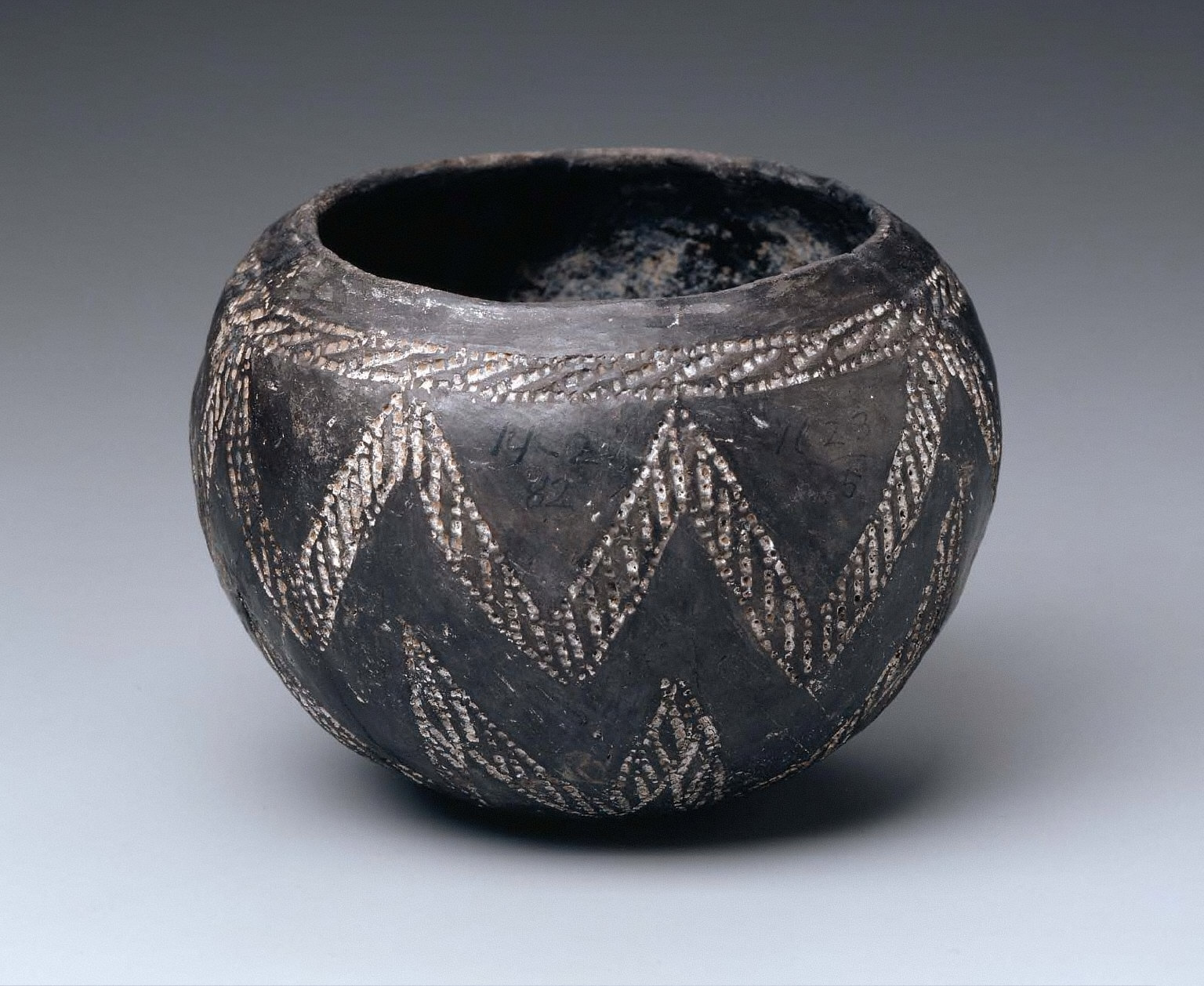 Black-polished bowl with white-filled, incised decoration